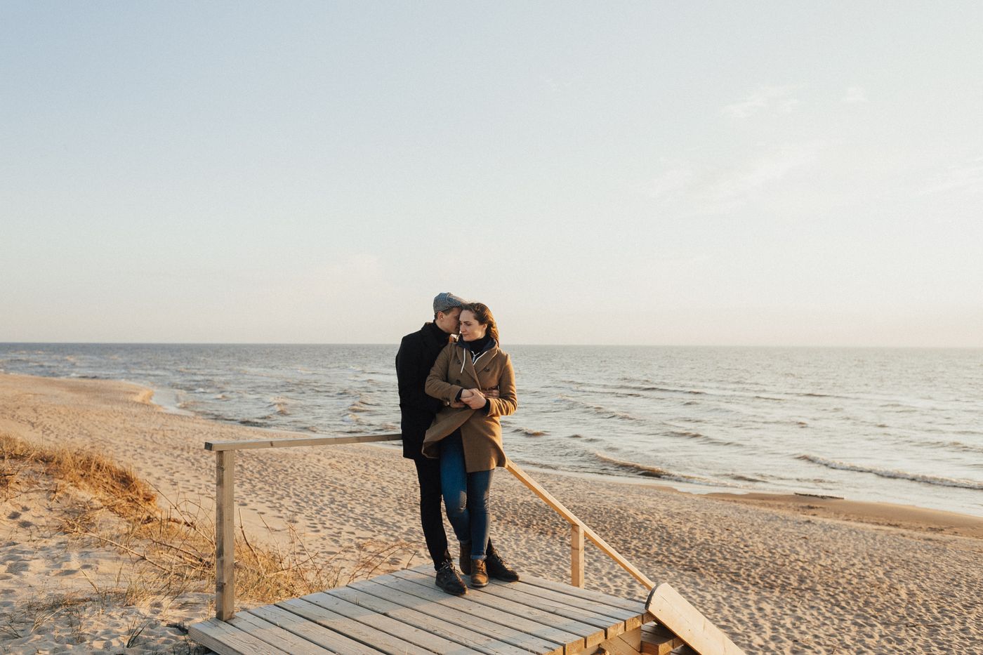 Couple embracing on a beach walkway at sunset